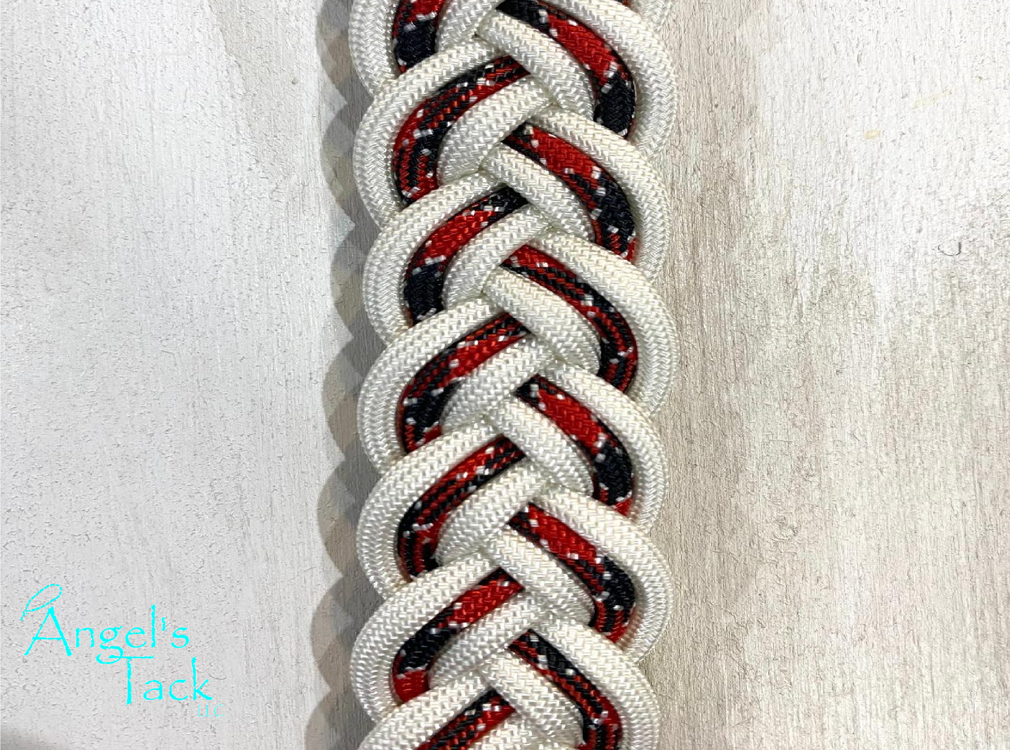 Red, black, and white patterned braided paracord barrel reins, close up