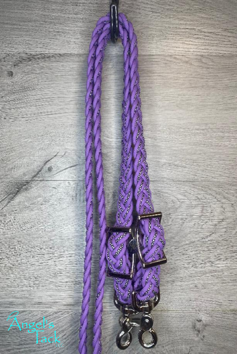 Light purple braided barrel reins with a diamond pattern hanging on a wooden wall.