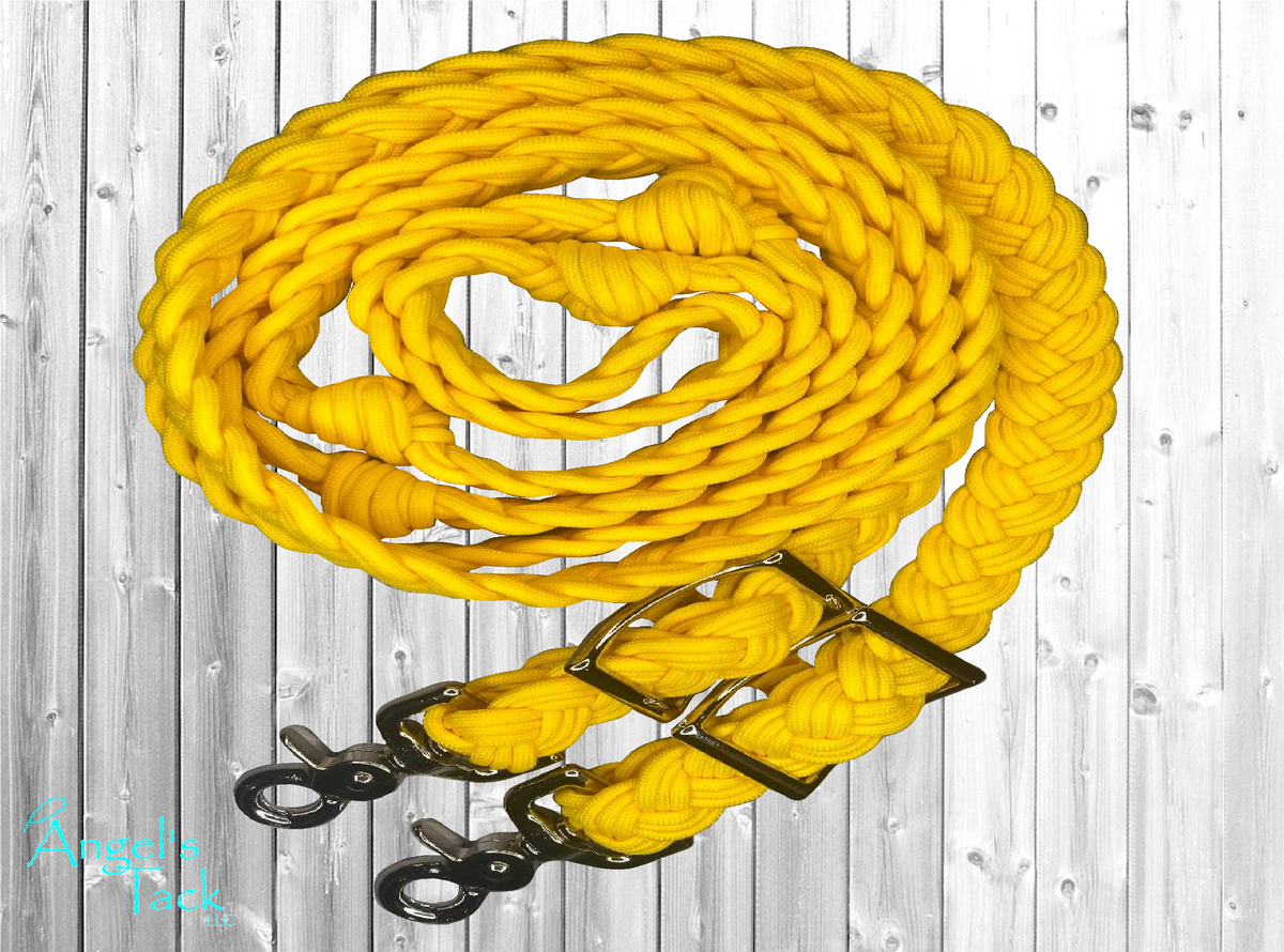 Yellow braided paracord barrel reins by Angel's Tack LLC. Shown coiled on a grey wooden background.